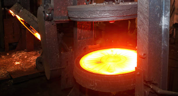 istock Press for forging glowing metal discs, sewer manholes isolated on black background. 2114860925