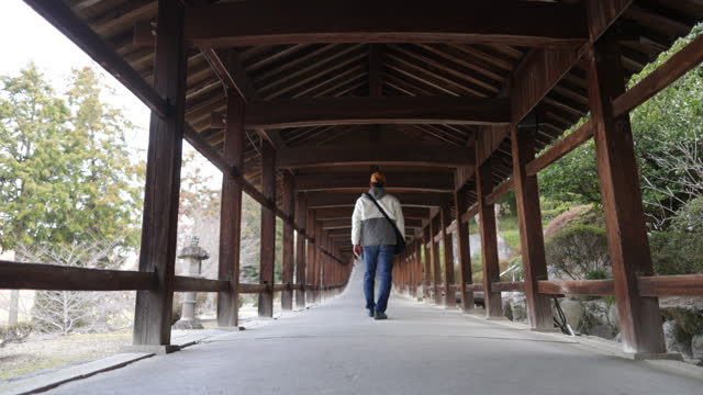 Rear view of Japanese tourist walking on shrine corridor in the morning