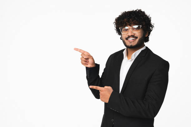 istock Young Hindu businessman in black suit pointing at copyspace isolated over white background. 2114870408