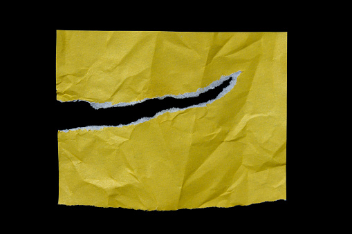 Yellow ripped paper isolated on black background. Torn paper.