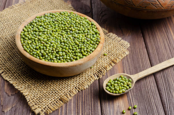 Green mung beans in a bowl with a spoon on a wooden table. Organic legumes. Vegan and vegetarian food. Rustic style. The concept of healthy eating. Horizontal orientation. Selective focus. stock photo