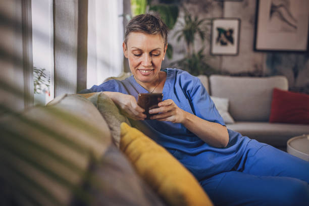 istock Woman in medical scrubs using phone 2114878771