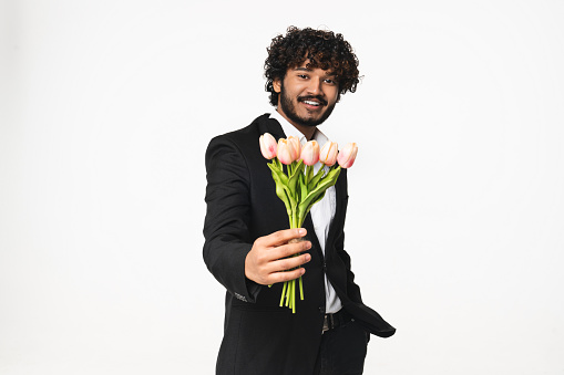 St. Valentine`s Day , birthday, International women`s day concept. Hindu young businessman giving flowers on a romantic date. Love and relationship. Presents - love language