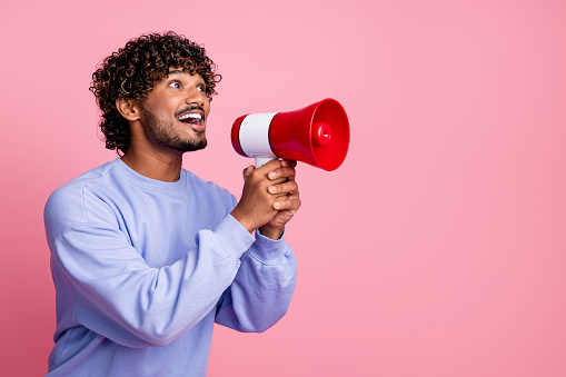 Photo of excited cheerful guy wear trendy clothes hold bullhorn tell say proclaim news isolated on pink color background.