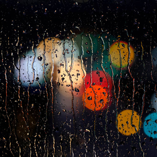 istock Rainy Wet Window at Night with Water Drops and City Lights 2114907433
