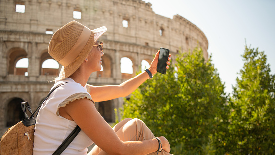 Woman taking selfie in front of Coliseum, Rome, Italy