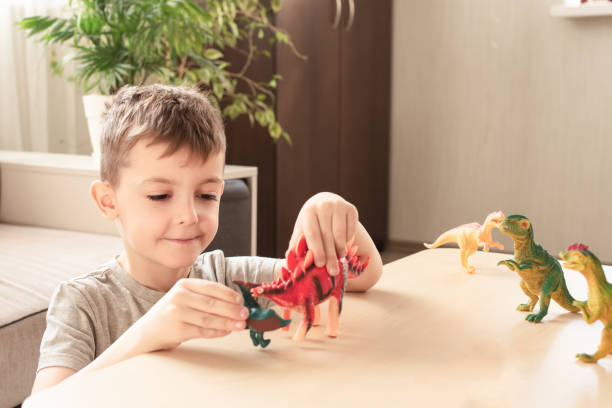 istock happy child learning about dinosaurs with realistic educational toys and dinosaur figurines. children safe at home 2114922827