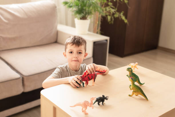 istock happy child learning about dinosaurs with realistic educational toys and dinosaur figurines. children safe at home 2114922828