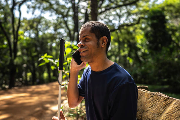 istock Visually impaired man talking on mobile phone at a public park 2114953397