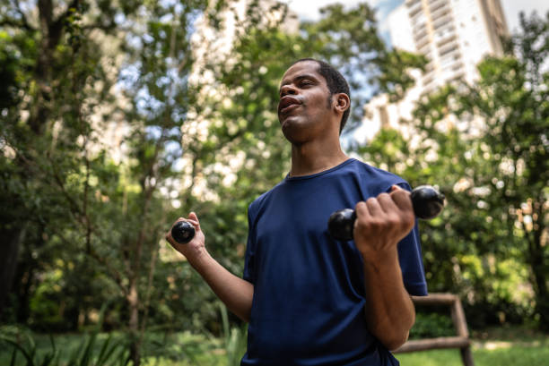 istock Visually impaired man exercising with dumbbells on a public park 2114953933