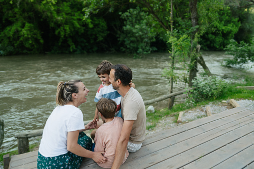 Photo of a young loving family, who enjoy being together on summer afternoon by the river