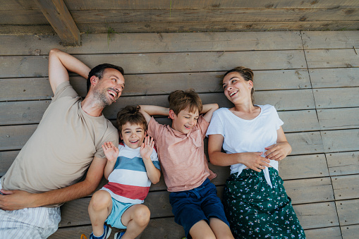 Photo of a young loving family, who enjoy being together on summer afternoon on the deck by the river