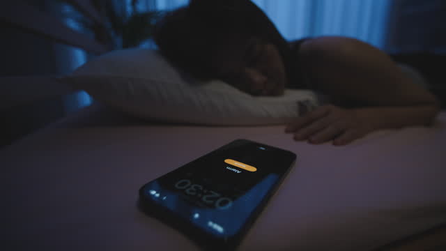 Sleeping women on bed awakened by smart phone alarm