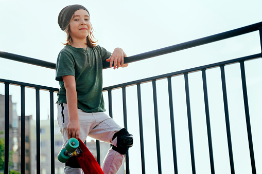 Portrait of a cute smiling little boy with skateboard in skateboard park.