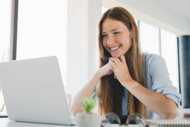 istock Young female freelancer working on laptop remotely at home office. 2114994360
