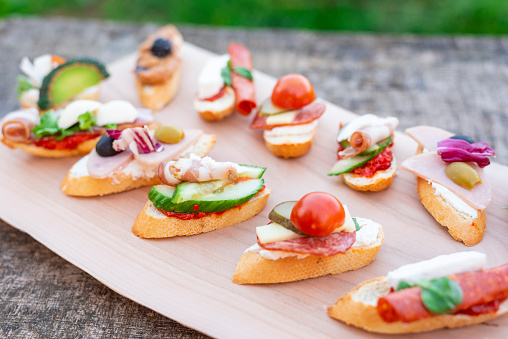 Finger food , various canapes with vegetables, ham, bacon , cheese and olives on wooden table.