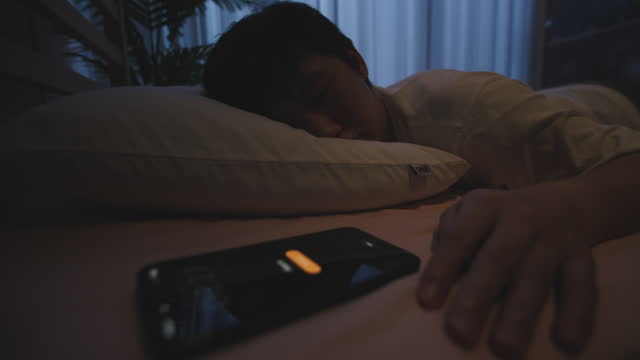 Sleeping man on bed awakened by smart phone
