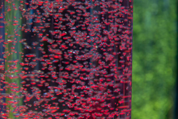 Abstract colorful holiday background. Close-up view of large amount of bubbles in glass tubes with red and green illuminated water. Soft focus. Festive backdrop theme.