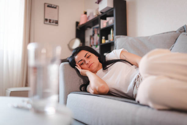 istock Young woman lying down while holding her stomach in pain 2115075985