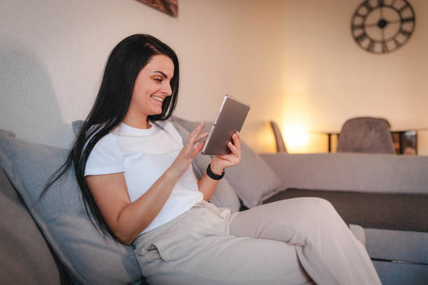 istock Beautiful young woman relaxing at home while using a tablet 2115078757