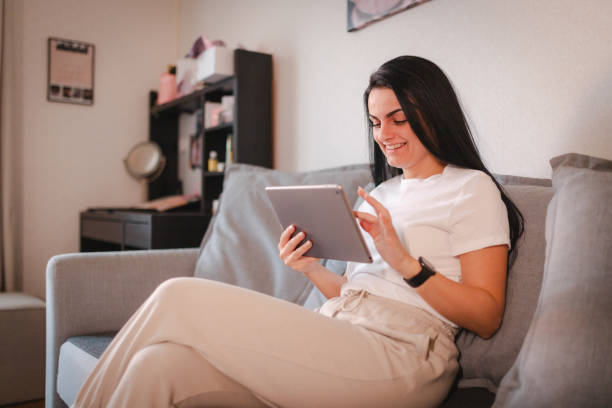 istock Beautiful young woman relaxing at home while using a tablet 2115079295