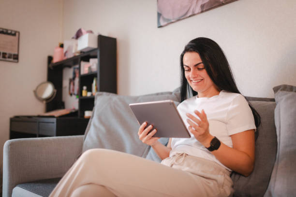 istock Beautiful young woman relaxing at home while using a tablet 2115079317