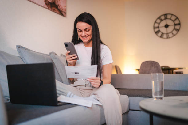 istock Young woman going through her bills at home 2115082621