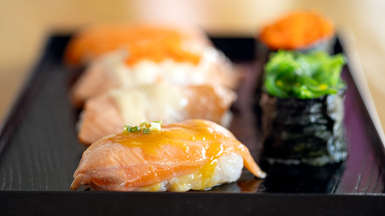 An enticing array of sushi, prominently featuring salmon and tobiko, artfully placed on a chic black serving plate