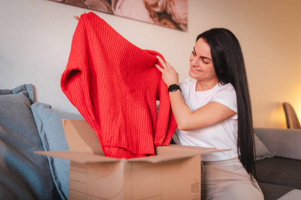 istock Smiling young woman checking out the clothes she ordered online 2115087898