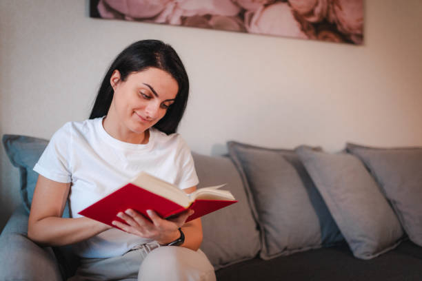 istock Beautiful young woman reading at home 2115097561