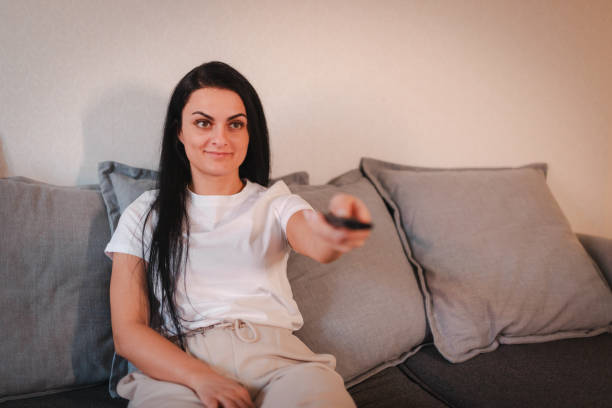 istock Young woman relaxing on the sofa at home while watching television 2115101775