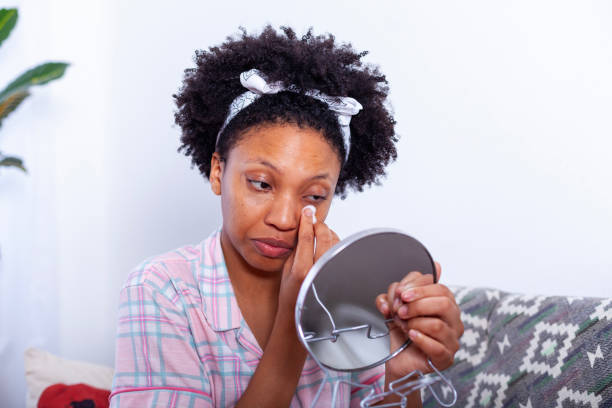 istock black woman applying concealer to dark circles at home 2115104401