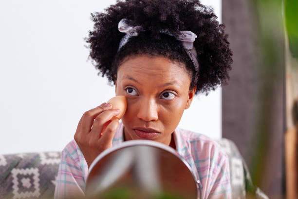 istock black girl putting on makeup at home holding a small mirror 2115105485