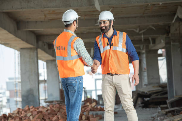 istock Male coworkers shaking hands at construction site 2115112223