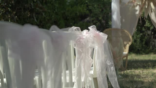 Slow revealing shot of decorated chairs ready for an exterior wedding reception