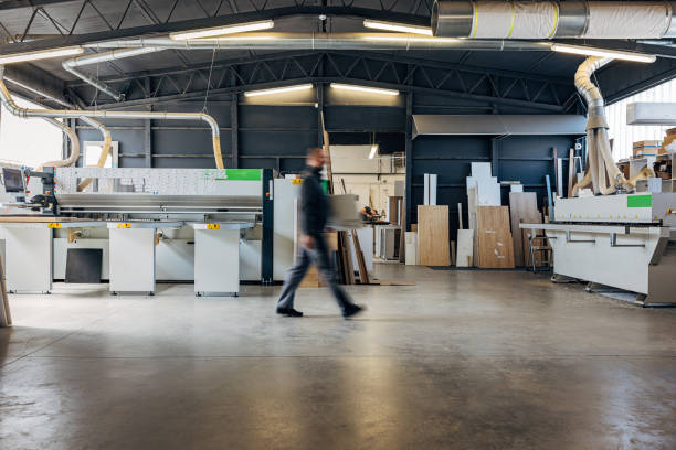 istock Interior of a workshop with a carpenter transporting wood to a processing machine 2115118727