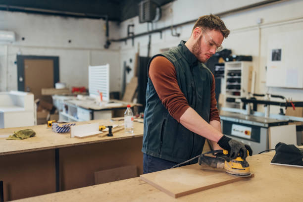 istock A focused worker with protective eyewear makes furniture in a workshop and uses an orbital sander 2115120001