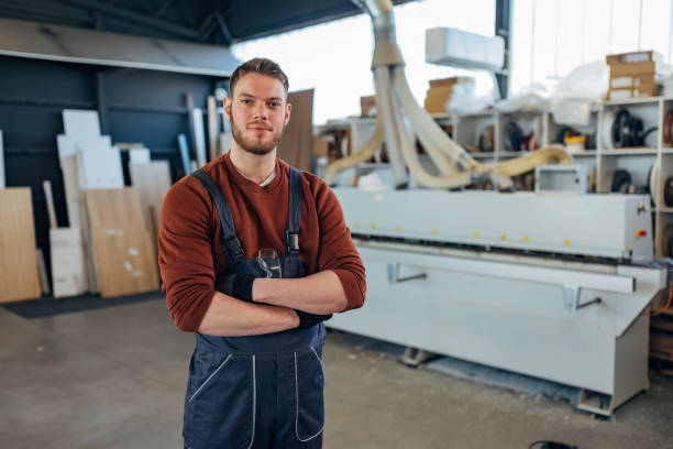 istock A handsome worker in coveralls and protective gloves looks directly at the camera while standing in the workshop 2115124101
