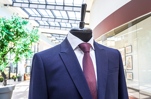 Male mannequin dressed in elegant suit with a tie in modern shopping mall