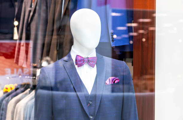 Mannequin dressed in elegant suit with a bow tie in a shop window. Men suits in a luxury clothing store