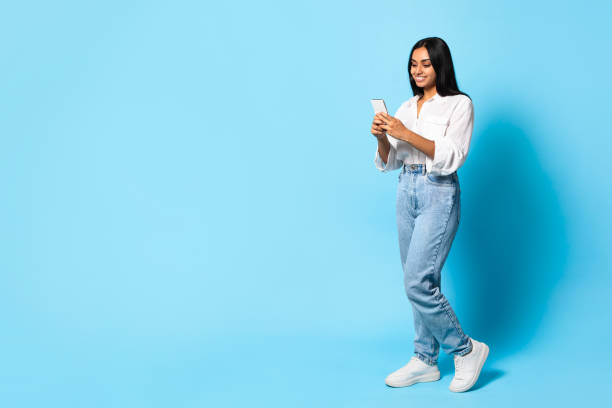 istock Indian Lady In Casual Using Smartphone Standing On Blue Background 2115141910