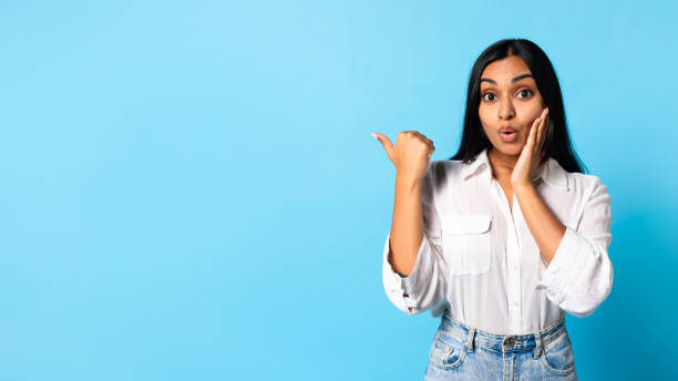 istock Emotional Indian Young Lady Pointing Aside With Her Thumb, Studio 2115141912