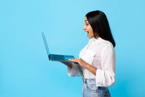 Side View Shot Of Excited Indian Woman Using Laptop, Studio