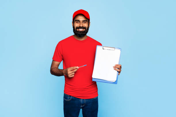 istock Indian delivery worker with clipboard on blue backdrop 2115159760