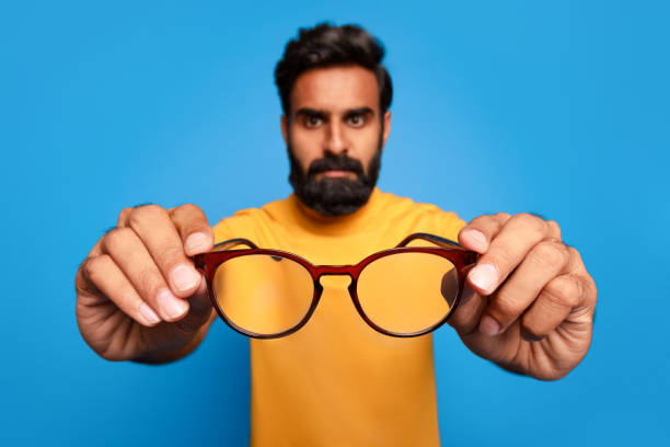 istock Middle aged indian man in yellow offering glasses to camera 2115159772