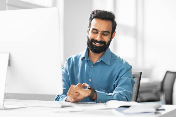 istock Man checking time on smartwatch at his workplace 2115225928