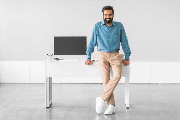 istock Confident indian man standing by office desk 2115226483