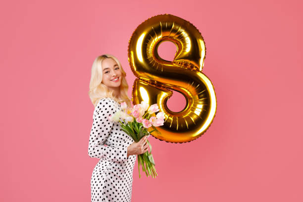 istock Blonde with tulips and number 8 balloon on pink backdrop 2115245455