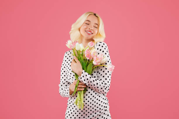 istock Blissful young woman hugging tulips on pink background 2115245457