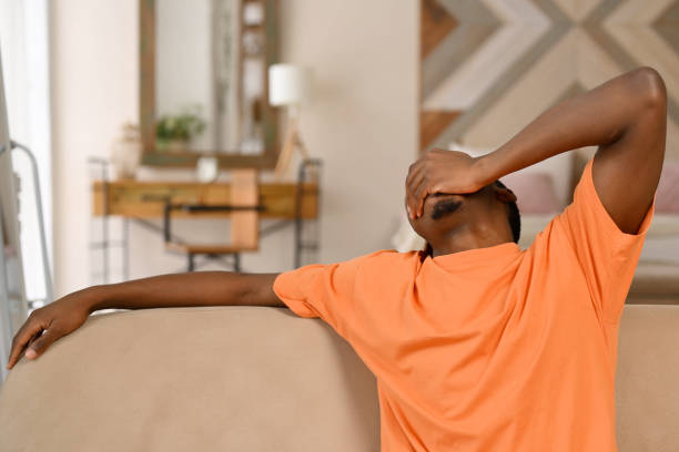 istock Young black guy yawns and stretches on the sofa 2115251321